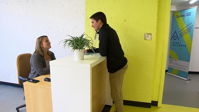 Une homme parle à une femme assise derrière un bureau à l'entrée de la clinique.