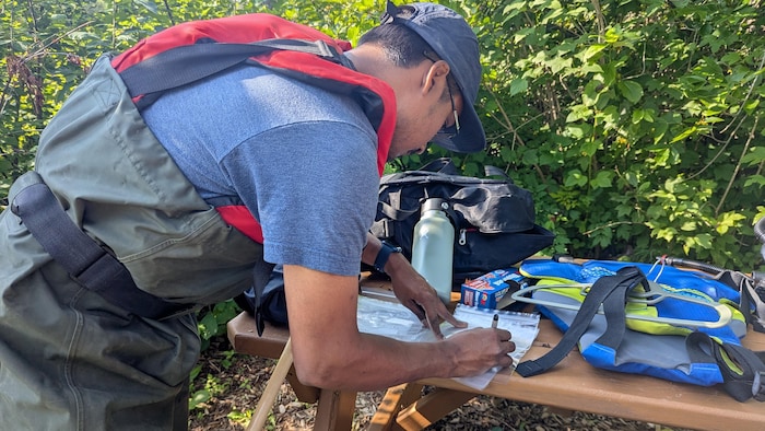 Sur une table de pique-nique, Akib Hasan identifie avec un marqueur des sacs Ziploc.