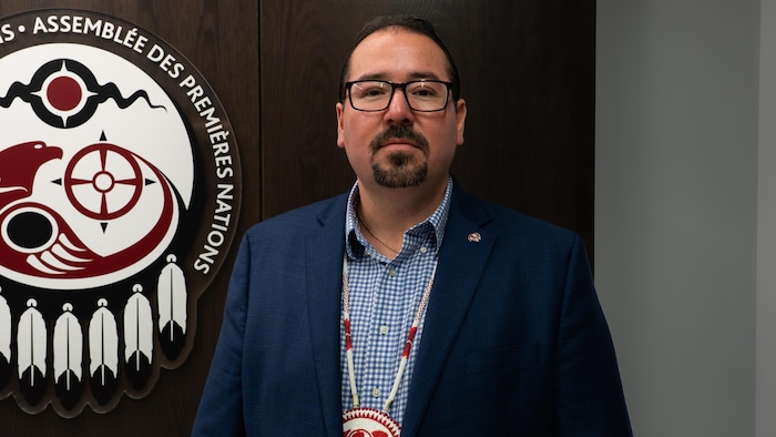 Abram Benedict pose dans les bureaux de l'Assemblée des Premières Nations à Ottawa. Il porte un collier perlé mohawk.
