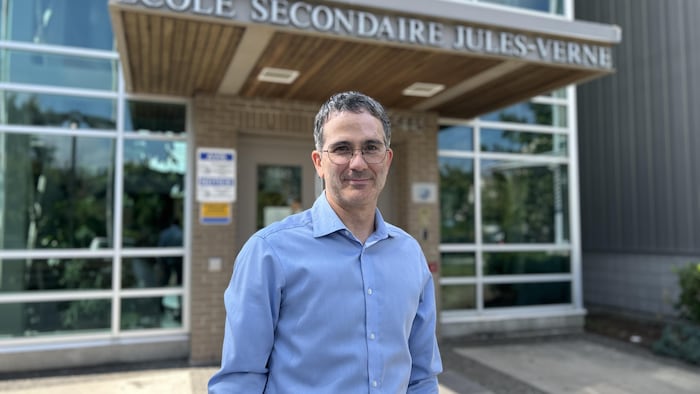 Alain Arbour se tient devant l'entrée de son école.