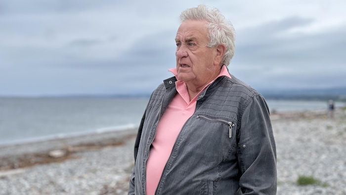 Alain Boucher est sur la berge et regarde l'horizon.