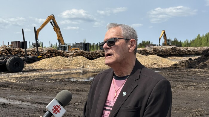 Le maire Alain Thibault devant une cour de bois. 