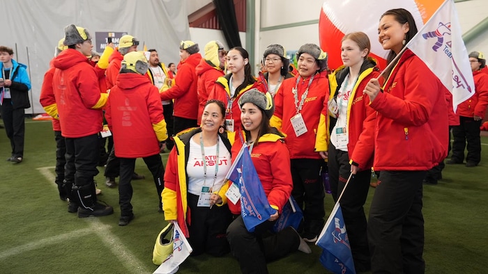 Des jeunes avec des manteaux rouge et jaune aux couleurs du Nunavut. 