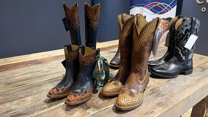 Cinq paires de bottes sur une table.
