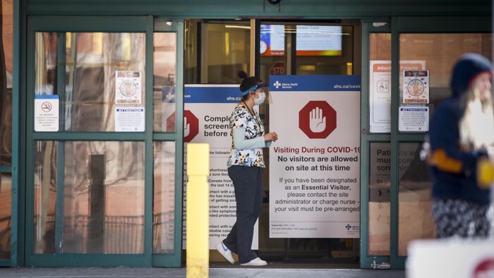 Une travailleuse de la santé passe devant la porte du centre hospitalier.