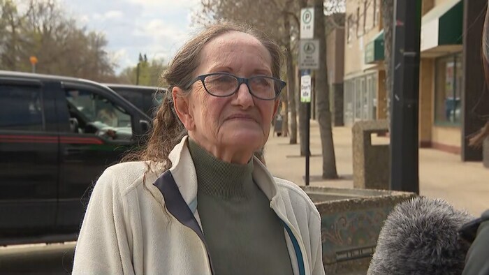 Une femme âgée portant des lunettes de vue écoute attentivement.