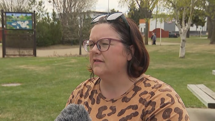 Une femme portant des lunettes de vue s'exprime devant un microphone.