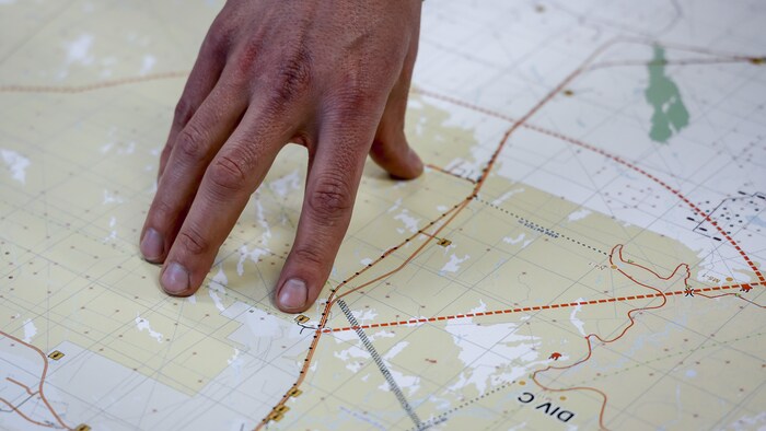 Une main pointe un endroit sur une carte.