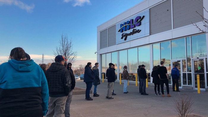 Des clients font la file à l'extérieur d'un magasin qui vend de l'alcool.
