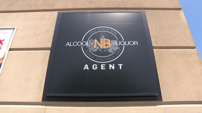 Une enseigne au logo d'Alcool NB et le mot « agent » sur la façade d'un dépanneur.