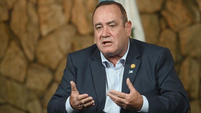Le président Alejandro Giammattei parle devant un drapeau du Guatemala.