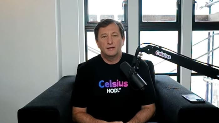 L'homme est assis devant un micro et porte un t-shirt arborant le logo de Celsius, ainsi que l'expression «HODL».