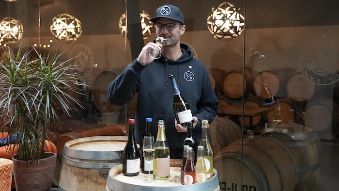 Alex Viol tient un verre et une bouteille de vin désalcoolisé à Sandhill Wines, à Kelowna, le 3 mars 2026.