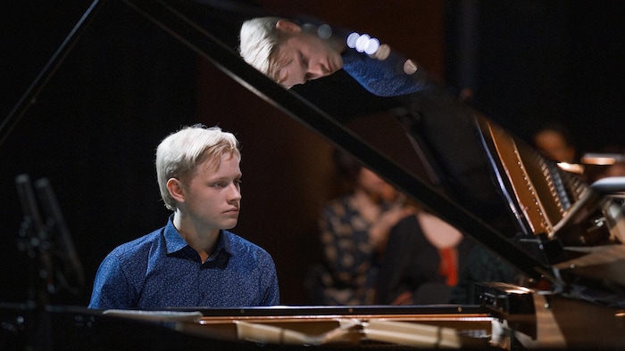 Un jeune homme blond est au piano.