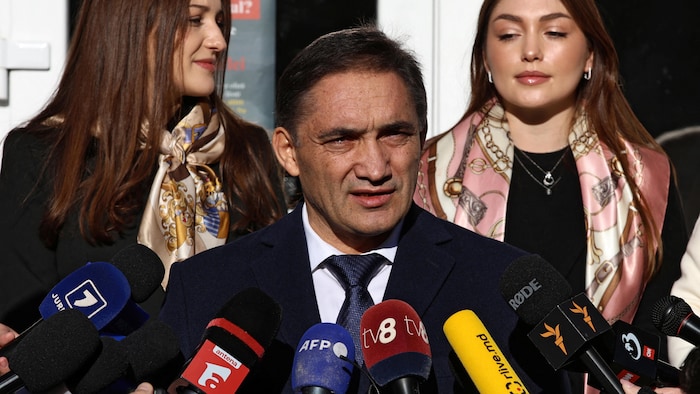 Un homme accompagné de ses deux filles s'adresse aux médias.