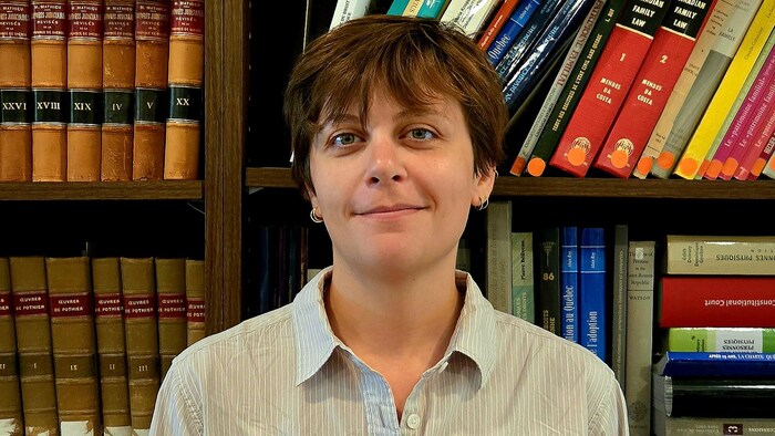 Alexandra Bahary-Dionne sourit à la caméra, debout devant des étagères remplies de livres.