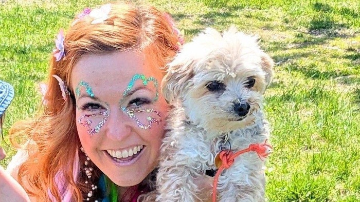 Alexandra  Ferron, fondatrice de l’École de magie Capucine, à l'extérieur avec un chien.