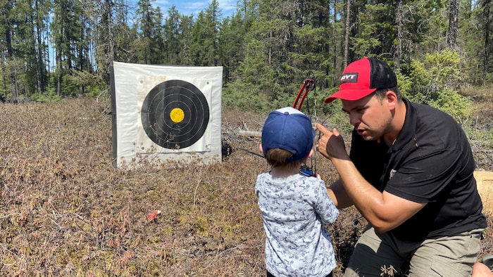 Alexandre Dupuis enseigne les rudiments du tir à l'arc à un jeune visiteur.
