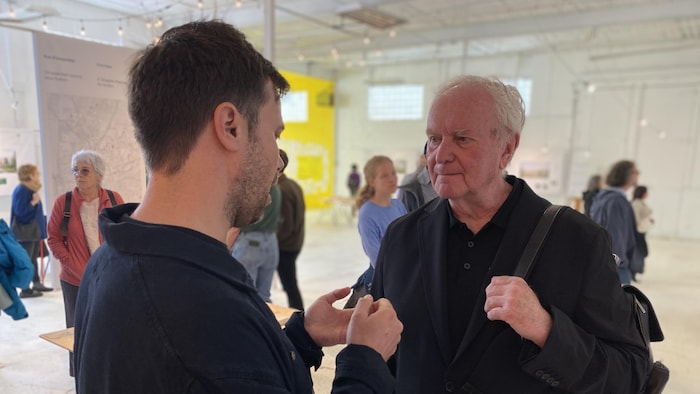 Le fondateur de l'organisme L'Ensemble, Alexandre Landry, et le maire Robert Benoît discutent dans l'exposition.
