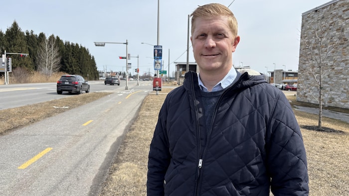 Alexandre Mailhot devant trois affiches électorales.