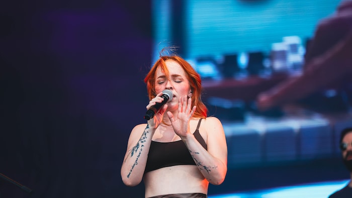 Une musicienne chante sur scène. 