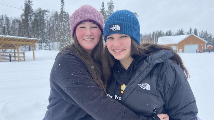 Alexia Milhomme debout à côté de Kim Lapointe dans une cour enneigée. 
