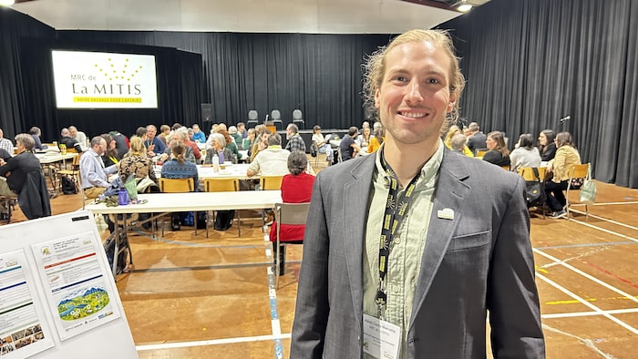 Portrait de l'aménagiste à la MRC de La Mitis, Alexis Couture-Marcotte, dans une salle communautaire où se tient un Sommet sur l'adaptation aux changements climatiques.