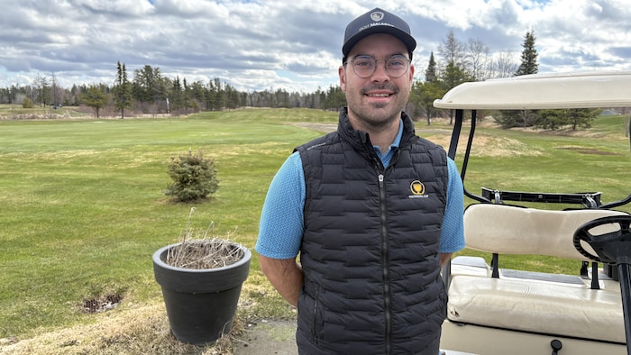 Alexy Vezeau, casquette du Golf Malartic sur la tête, pose pour la photo en souriant. Derrière lui, un vert de golf.
