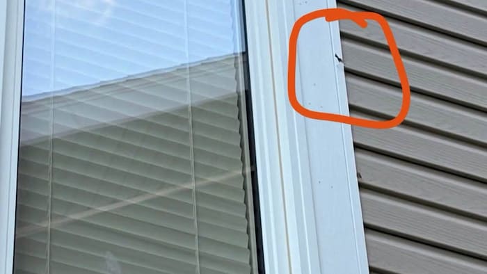 L'impact d'une balle près d'une vitre extérieure d'une maison.
