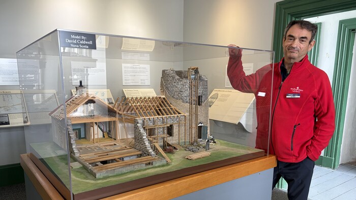 Une homme présente une maquette d'un phare en construction.