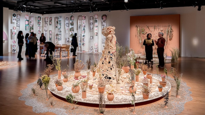 Des œuvres d'art sont exposées dans une salle au milieu de plantes. 