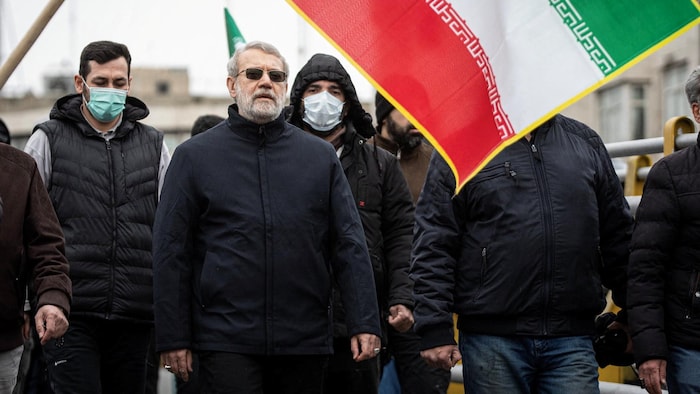 Le chef de la sécurité iranienne, Ali Larijani, dans une manifestation, sous un drapeau iranien. 