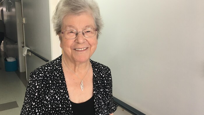 Aline Cyr souriante dans le couloir de la résidence pour personnes âgées qu'elle habite.