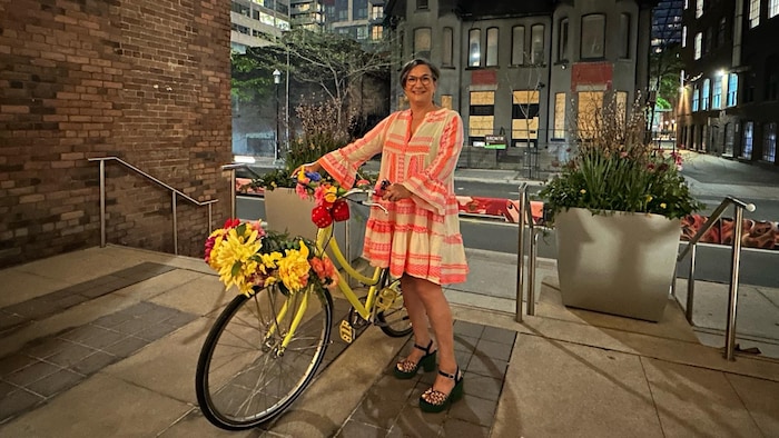 Une femme montre son vélo coloré.