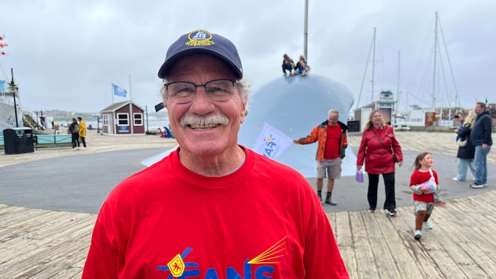 Allan Mountford devant une sculpture représentant une vague.