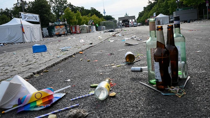 Des bouteilles et des déchets jonchent la rue.