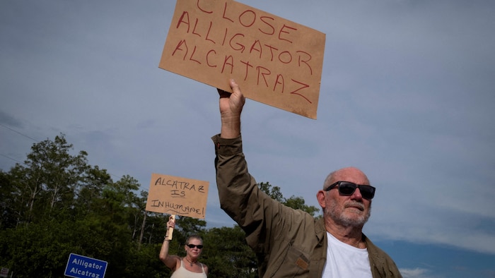 Un homme et une femme brandissent des pancartes avec l'inscription «Fermez l'Alcatraz des alligators».