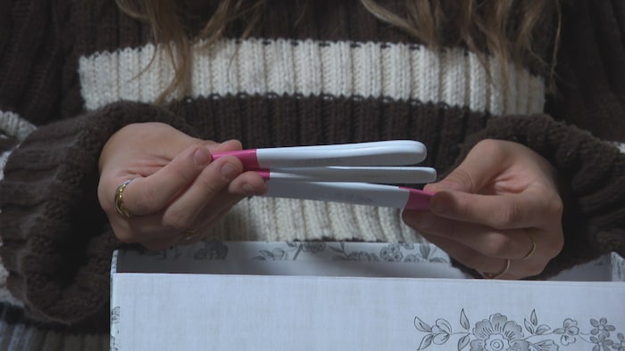 Les mains d'une femme qui tient des tests de grossesse.