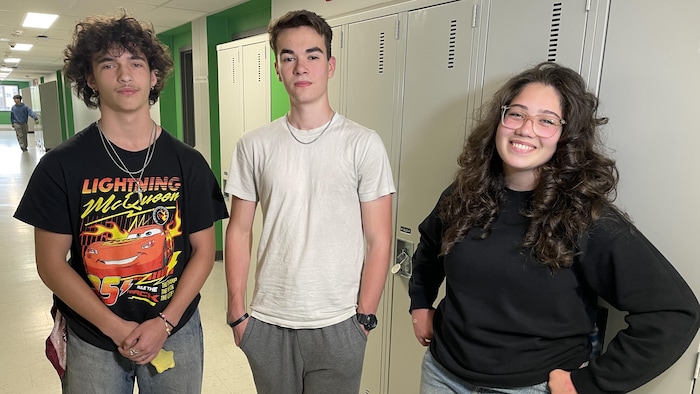 Trois adolescents devant des casiers d'école.