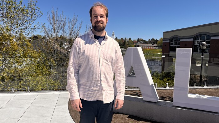 Un homme pose fièrement devant les lettres géantes ALMA au centre-ville d'Alma.