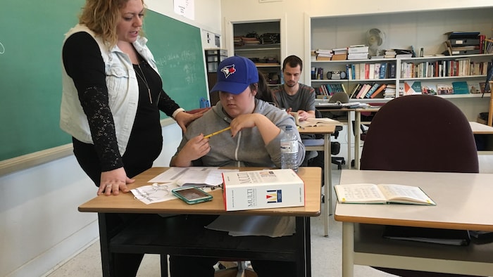 Une enseignante permet aux élèves dans son cours d'éducation aux adultes d'apprendre à leur rythme.