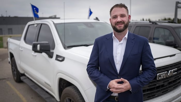 Cameron Davies est debout devant une camionnette.