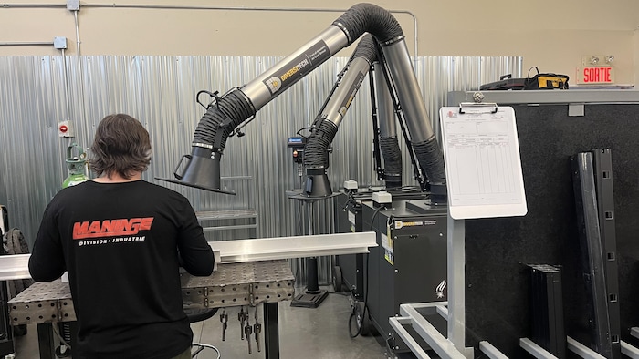 Une personne de dos travaille dans une usine.