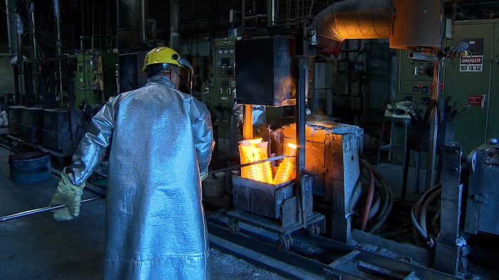 Un homme travaille de l'aluminium en fusion dans une usine.