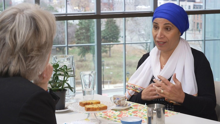 Amal Elsana-Alhjooj, de face, discute avec la journaliste Sophie Langlois, de dos. Toutes deux sont assises à une table.