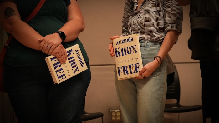 Des gens tiennent le livre d'Amanda Knox en faisant la file pour la rencontrer à Vancouver, le 2 juin 2025.