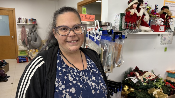 Une personne souriante dans un local plein d'objets usagés.