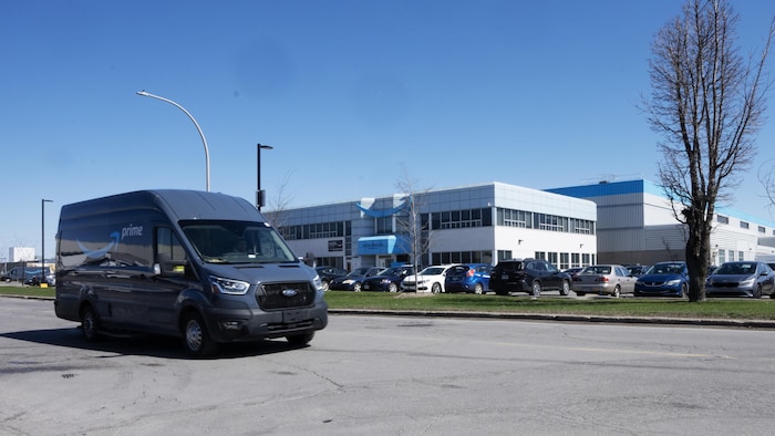 Un camion d'Amazon roule devant un entrepôt.