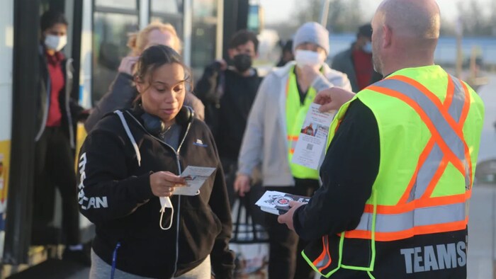 Un organizador sindical reparte panfletos informativos a los trabajadores que bajan del autobús frente a la sede de la empresa Amazon en la ciudad de Hamilton. 