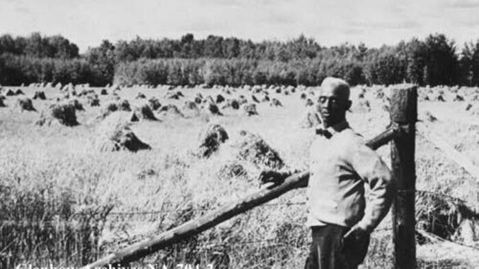 J. D. Edwards, devant un champ de céréales.